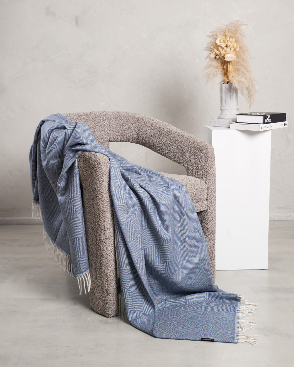 A PETROL BLUE ALPACA BLANKET IN A CHAIR IN A EMTY ROOM 