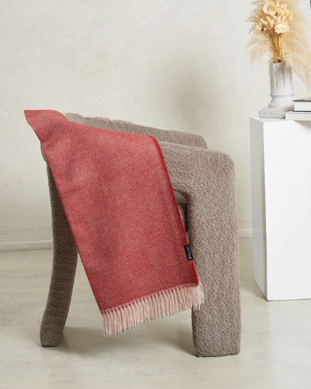 white and red alpaca blanket in a modern armchair color dark grey 
