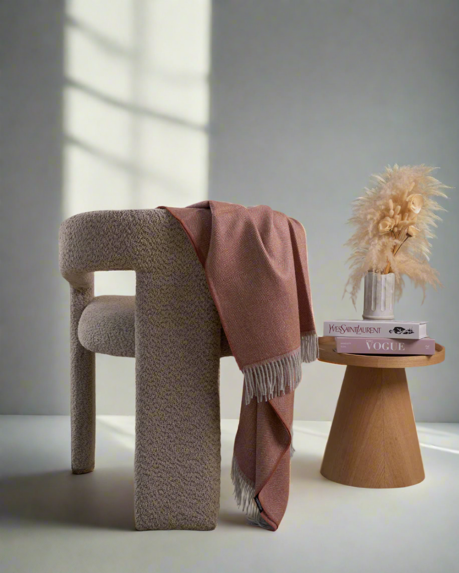 a alpaca blanket redwood color in a armchair in a Scandinavian room in day light. 